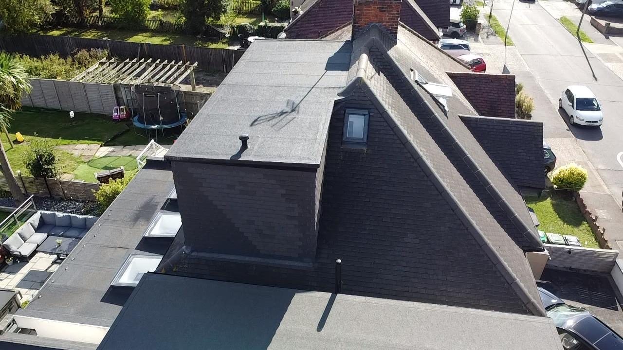 Slate-clad rear dormer above a single-storey extension, seen from the garden side