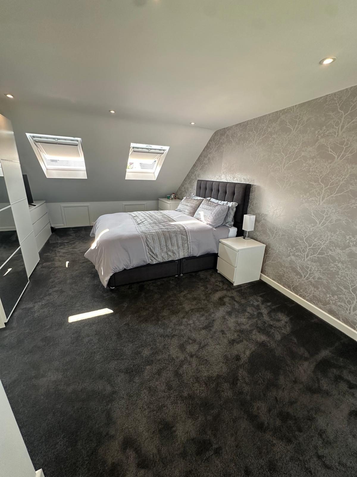 Loft master bedroom with twin Velux windows and a patterned feature wall