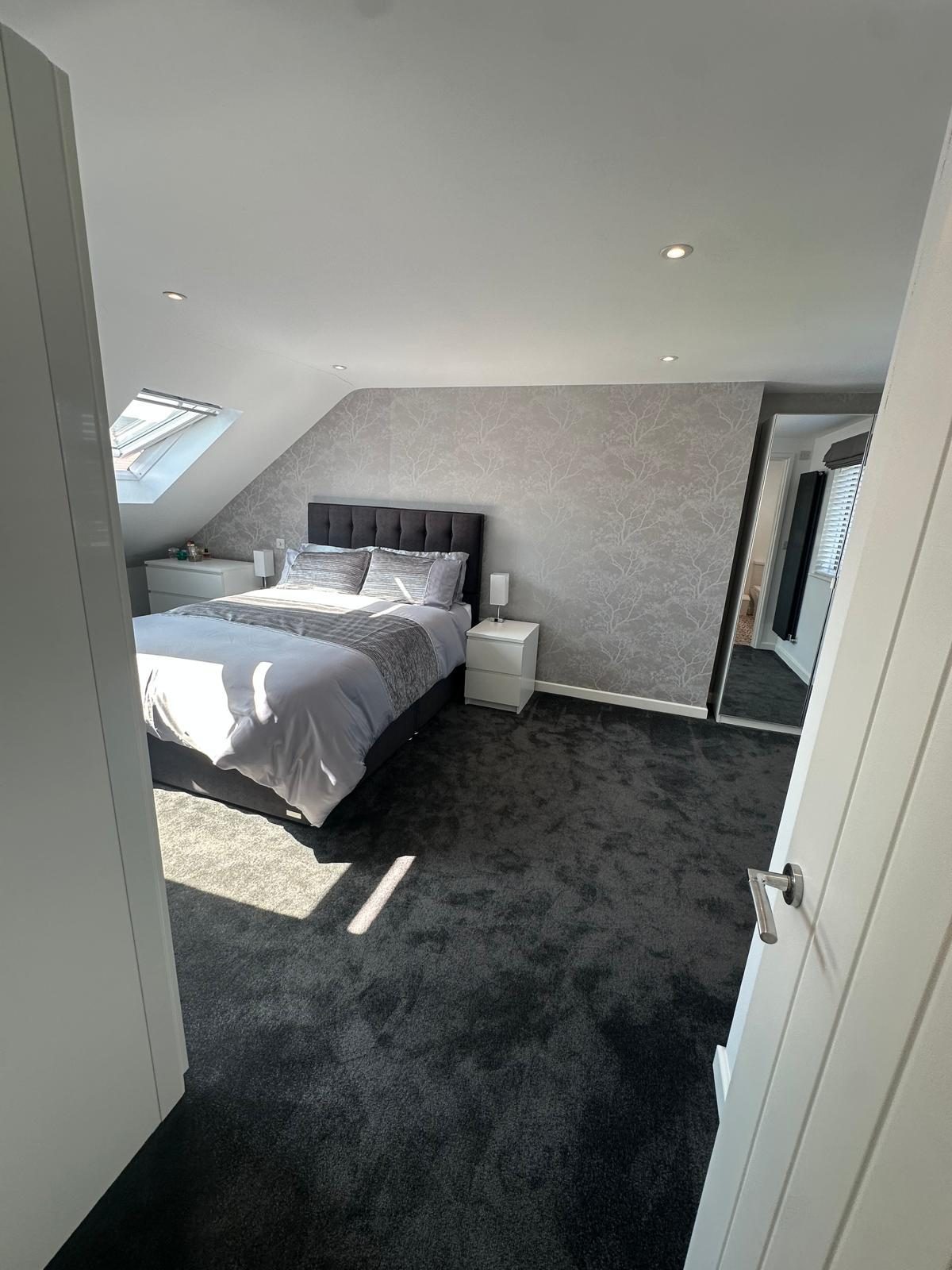 Loft bedroom seen from the doorway, showing the sloped ceiling and Velux