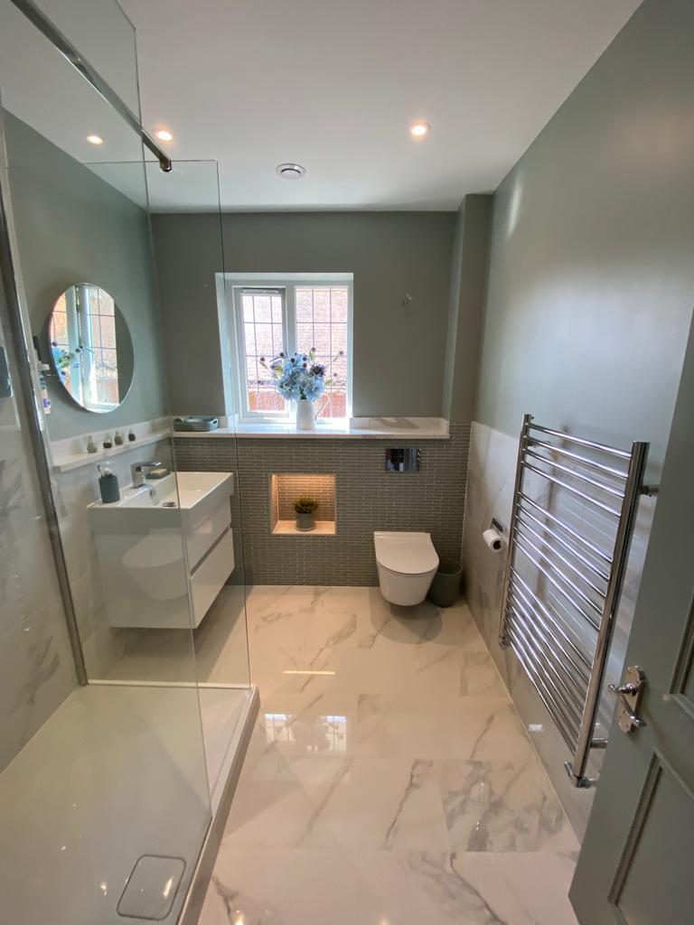 Sage-green and marble bathroom with lit niche and chrome radiator, Tadworth