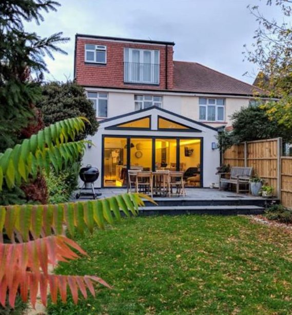 Glazed-gable rear extension glowing at dusk, Worcester Park